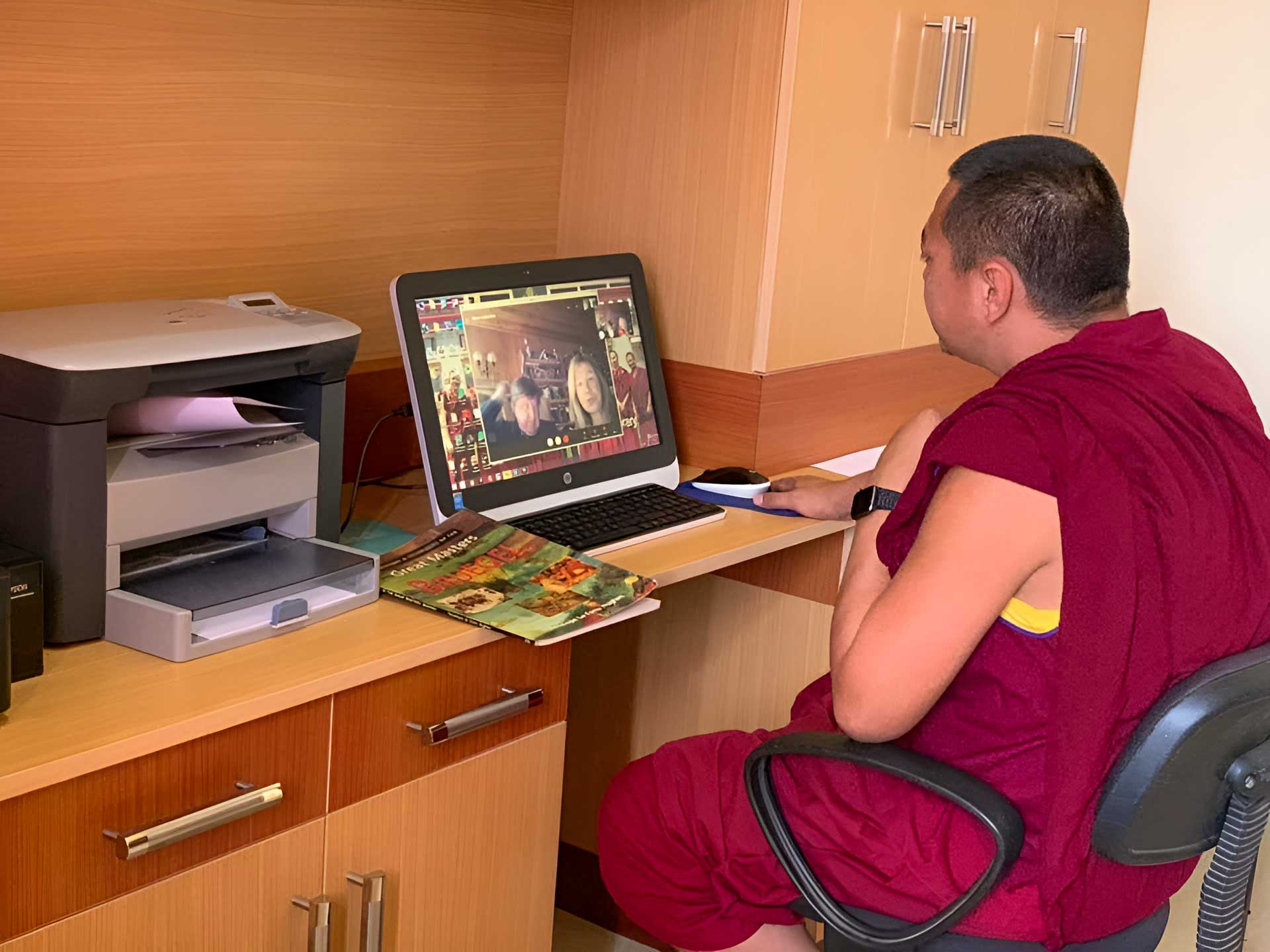 A monk using a laptop computer at a desk.
