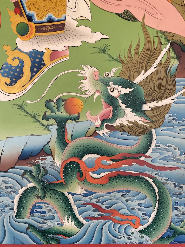 Wall painting of a stylised dragon or sea creature amidst green waves and clouds.