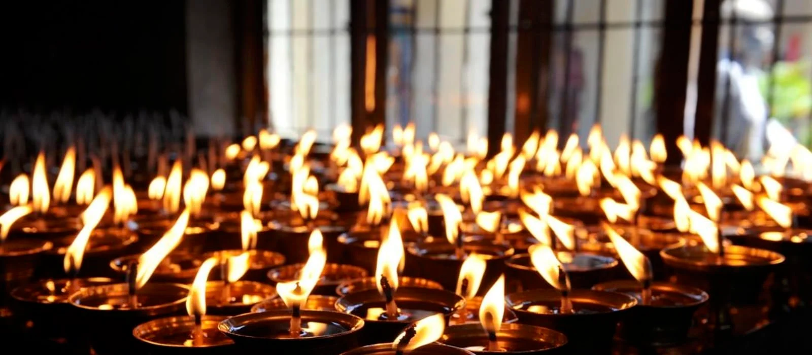Many rows of lit candles flickering in a dark interior.
