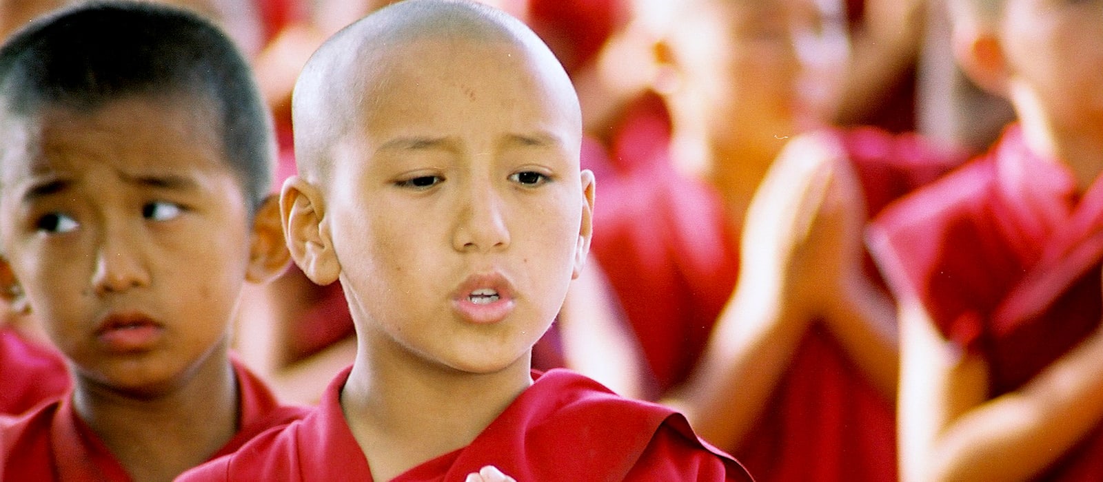A close-up of a child in maroon robes with an open expression.