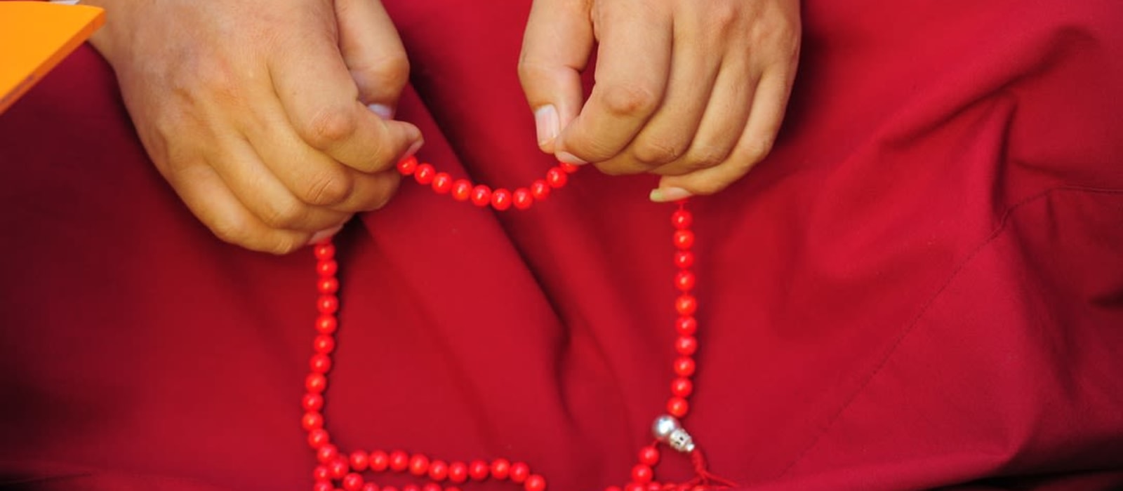 Hands holding red prayer beads (mala).
