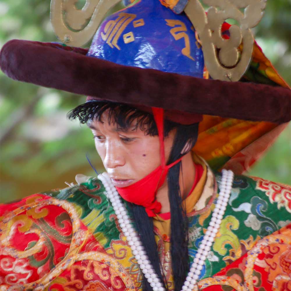 Close up portrait of monk wearing traditional masked dance attire.