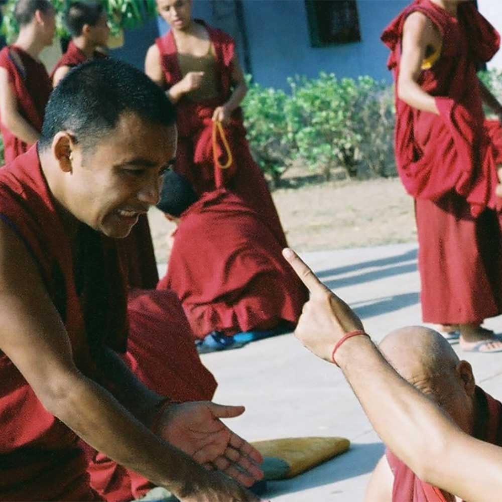A monk gesturing while speaking to others.