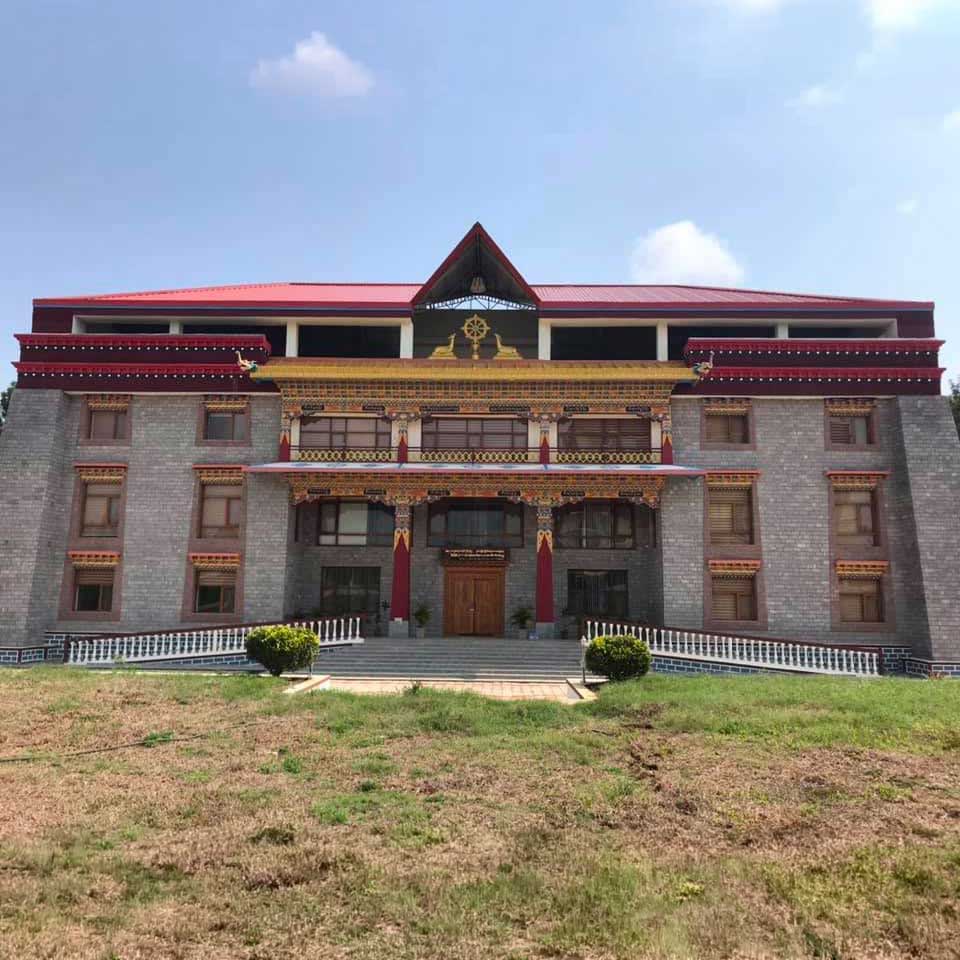 A multi story white building with red trim which is the tashi lhunpo library.