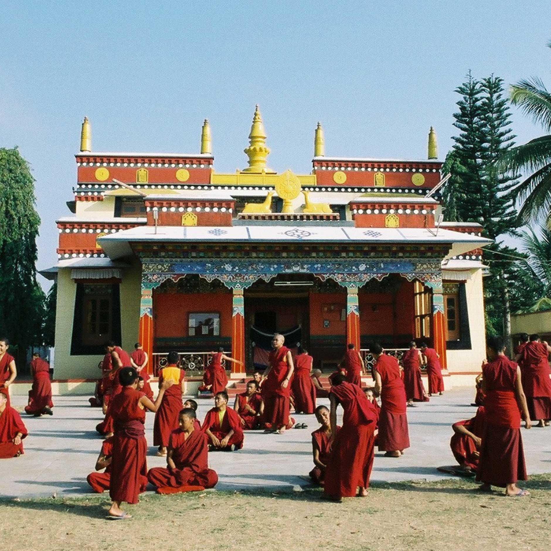 Monks seated in a courtyard in front of the tantric college which used to be the first temple.