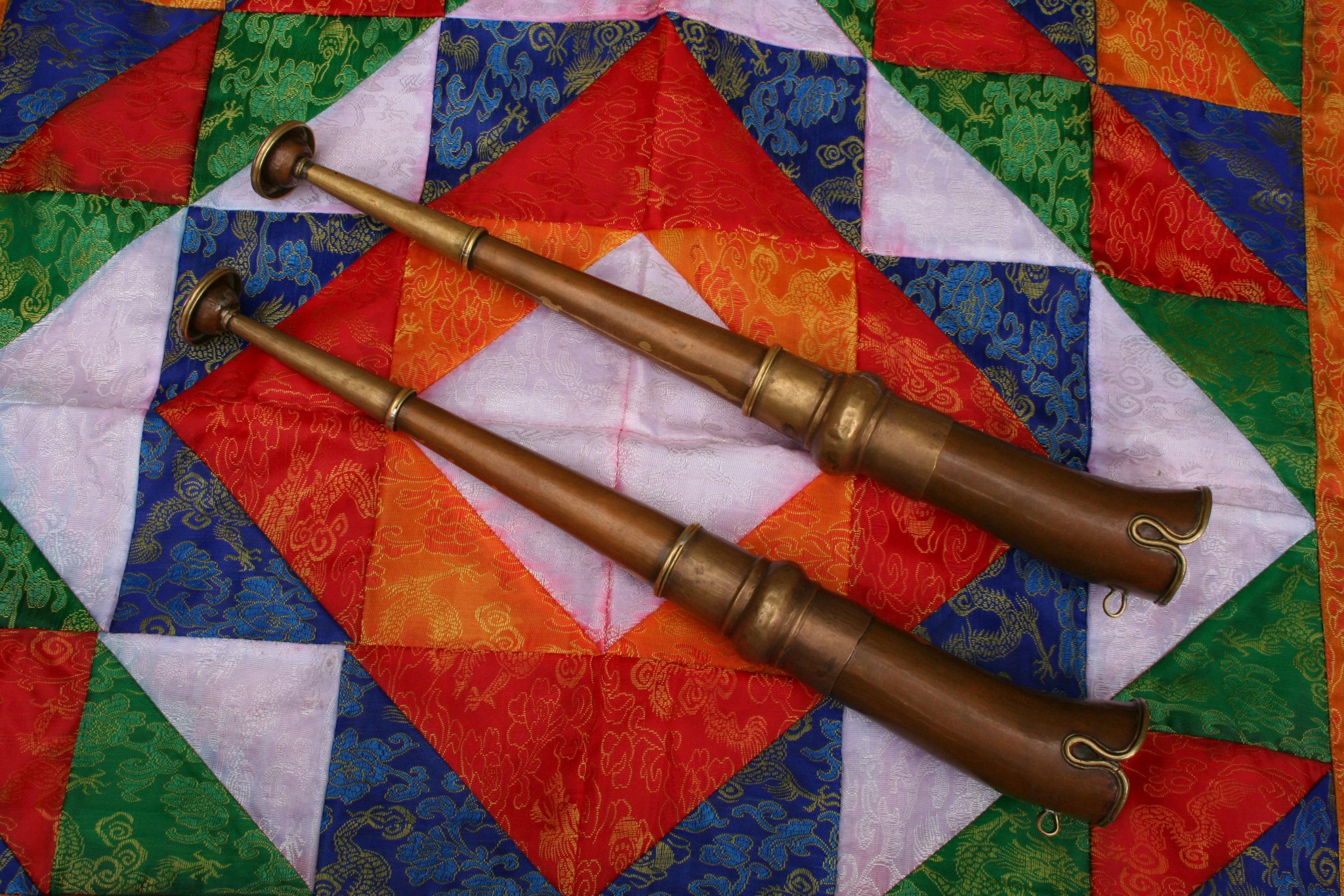 Two long Tibetan trumpets (dungchen) over a colourful fabric.