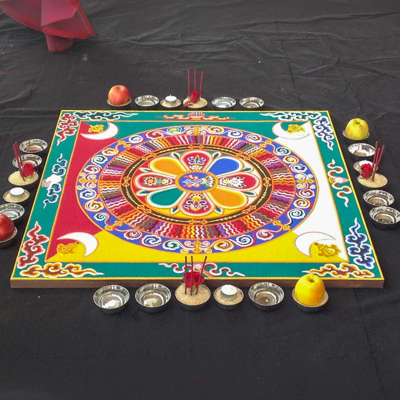 A sand mandala being created on a large wooden platform.